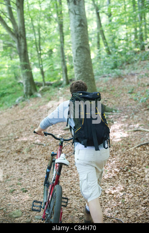 Mann schob Fahrrad im Wald, Rückansicht Stockfoto