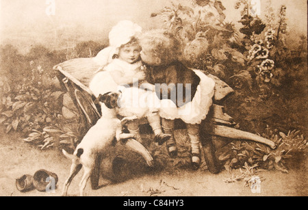 Alte Ansichtskarte von 1902 mit zwei kleinen Kindern und einem Hund. Älterer Junge seine Schwester zu küssen. Stockfoto