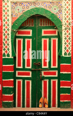 Traditionelle marokkanische Pantoffeln/Hausschuhe gegen hölzerne & gefliesten marokkanischen Tür in der Medina, Essaouira, Marokko, Nordafrika Stockfoto