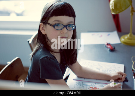 Mädchen sitzen am Schreibtisch mit Malbuch Stockfoto