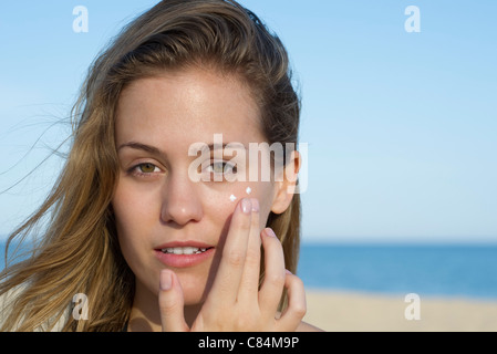 Frau, die Anwendung von Sonnenschutzmitteln am Strand, Porträt Stockfoto