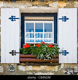 Schiebefenster in einem kornischen Cottage mit künstlichen hölzernen Fensterläden und Blumenkasten voll von bunten Blumen Stockfoto