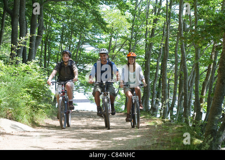 Freunde auf Fahrrädern nebeneinander durch Wald Stockfoto