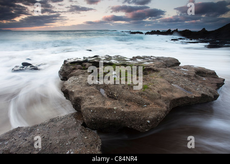 Wellen über die Felsen am Strand Stockfoto