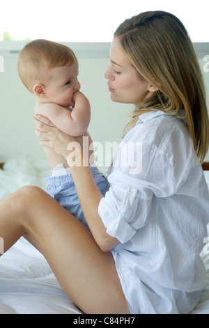 Mutter sitzt auf Bett, halten Baby auf Schoß Stockfoto