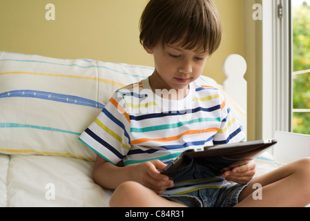 Junge sitzt auf dem Bett, mit digital-Tablette Stockfoto