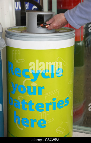 Eine Person, die gebrauchte Batterien in einen Recycling-Behälter wirft. England, Großbritannien Stockfoto