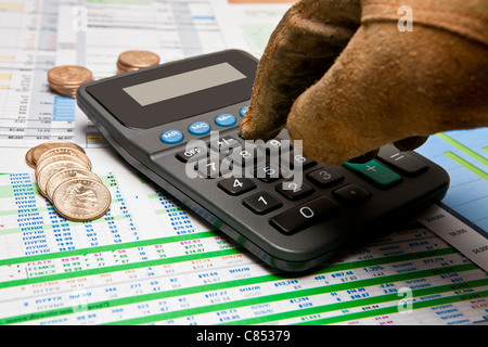 behandschuhten Hand am Rechner und Dollar uns Münzen auf verschiedenen Geschäftsdokumenten Stockfoto