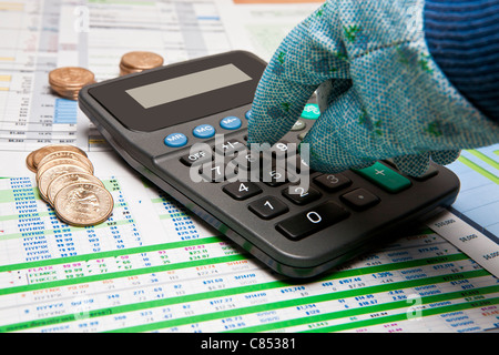 behandschuhten Hand am Rechner und Dollar uns Münzen auf verschiedenen Geschäftsdokumenten Stockfoto