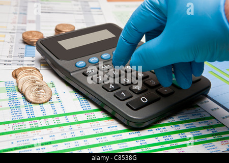 behandschuhten Hand am Rechner und Dollar uns Münzen auf verschiedenen Geschäftsdokumenten Stockfoto