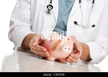 Frau Doktor Holding fürsorgliche Hände auf ein Sparschwein mit Bandage. Stockfoto