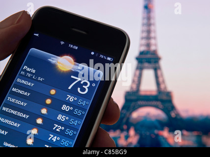 Eiffelturm in der Abenddämmerung mit Hand Apple iPhone mit Bildschirm Woche Urlaub Sonne auf Wetter-Smartphone-Anwendung Stockfoto