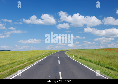 Straße durch Felder mit dramatischen Himmel. Franken, Bayern, Deutschland. Stockfoto