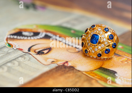 Indischen blauen Saphir und gold Diamantring auf einem traditionellen indischen Öl-Gemälde von einem Womans Gesicht Stockfoto