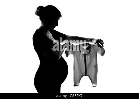 eine schöne kaukasischen schwangere Frau mit Baby-Kleidung in Silhouette auf weißem Hintergrund Studio isoliert Stockfoto