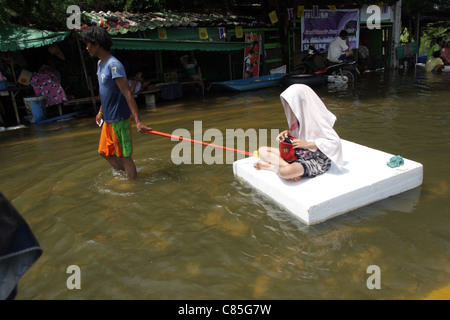 Thais waten durch das Wasser mit Schaum als Hochwasser Ursachen Verwüstung in Ayutthaya, Thailand Stockfoto