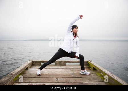 Frau, dehnen am Dock vor dem Joggen, Puget Sound, Seattle, Washington, USA Stockfoto