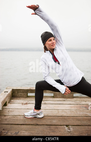 Frau, dehnen am Dock vor dem Joggen, Puget Sound, Seattle, Washington, USA Stockfoto