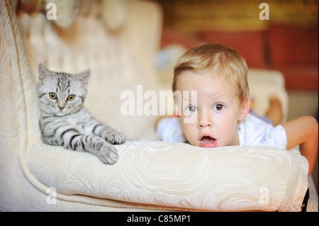 Kind und Katze auf einem weißen Sofa freuen Stockfoto