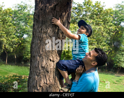 Vater seinen Sohn, einen Baum zu klettern zu helfen Stockfoto