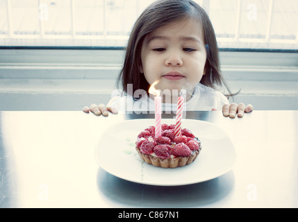 Kleines Mädchen bläst Kerzen auf Geburtstagskuchen Stockfoto