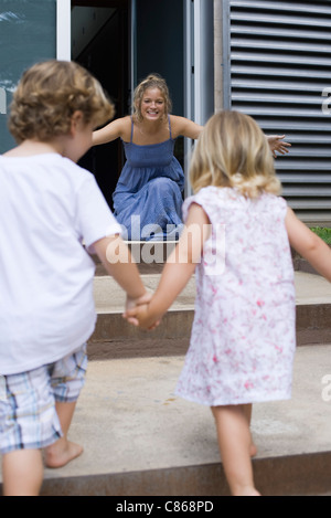 Junge Geschwister Hand in Hand, laufen in Richtung Mutter Stockfoto