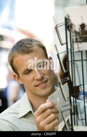 Männliche Touristen auf der Suche auf Postkarten Stockfoto