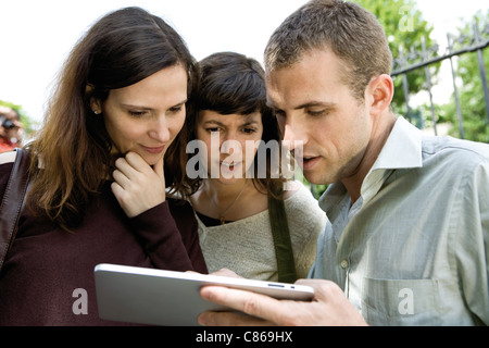 Freunde betrachten digitaler Tablet im freien Stockfoto