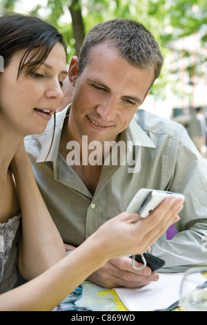 Paar auf der Suche auf Handy zusammen im freien Stockfoto