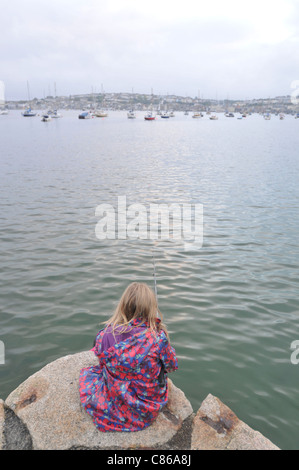 Ein 8 Jahre altes Mädchen Angeln in Flushing, Cornwall mit Falmouth im Hintergrund Stockfoto