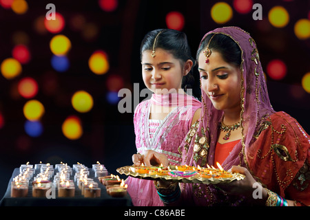 Mutter ein Tablett mit Diyas zu halten, während ihre Tochter blickt auf Stockfoto