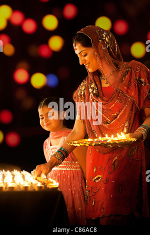 Mutter Diyas auf einem Tisch platzieren, während ihre Tochter schaut Stockfoto