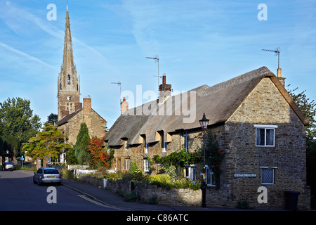 Dorfkirche Großbritannien. Kings Sutton Pfarrkirche und strohgedeckte Hütten Oxfordshire England Großbritannien Stockfoto