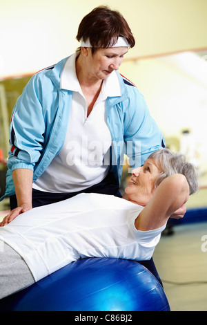 Ältere Frau Bauch Übungen mit ihrem Trainer im Fitness-Studio Stockfoto