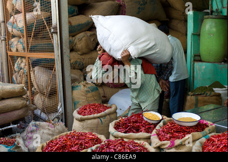 Rote Chilis zum Verkauf an Khari Baoli Gewürze und getrocknete Lebensmittel Markt und Porter trägt schwere Last, Alt-Delhi, Indien Stockfoto