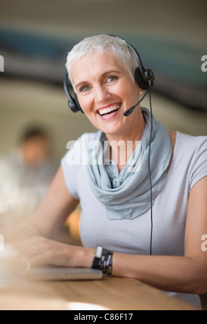 Ältere Frau im Kopfhörer mit laptop Stockfoto