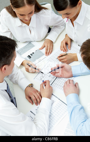 Erhöhte Ansicht der vier Unternehmer arbeiten mit Finanzdaten Stockfoto