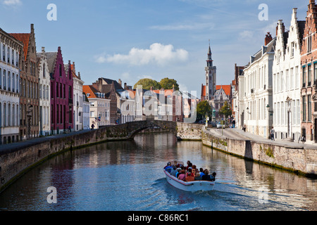 Touristenboot auf dem Kanal entlang der Spinolarei und Spiegelrei in Bruges,(Brugge), Belgien mit der Poortersloge in der Ferne. Stockfoto