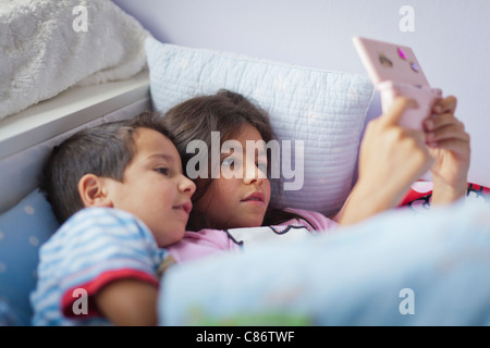 Kinder spielen auf dem Nintendo DS im Bett Stockfoto