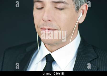 Nahaufnahme eines heiteren Geschäftsmann seine Kopfhörer mit geschlossenen Augen hören. Stockfoto