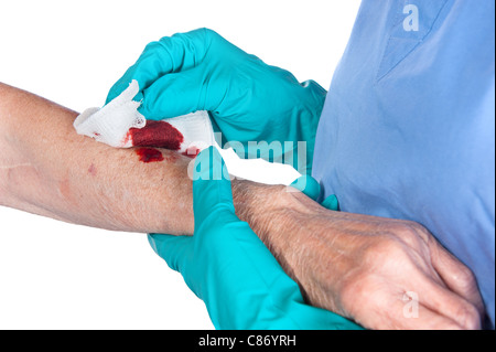 Eine Krankenschwester neigt dazu, eine blutige Wunde auf eine ältere Frau Arm Stockfoto