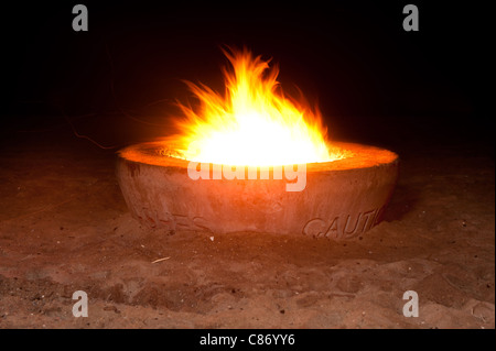 Ein loderndes Feuer in einem Zement-Feuerstelle am Strand während der Nachtzeit. Stockfoto