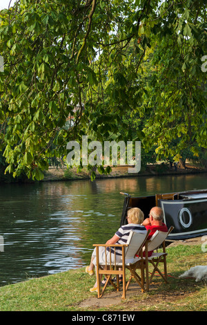 Paar, sitzen ihre Narrowboat am Ufer des Flusses Avon im späten Nachmittag Sonne, Stratford Warwickshire, England, UK Stockfoto