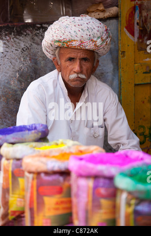 Indischer Mann verkaufen Pulver Lackfarben für Holi Festival zum Verkauf an Katala Bazar in Jodhpur, Rajasthan, Nordindien Stockfoto