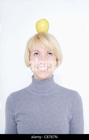 Nahaufnahme von junge Frau balancieren Obst auf Kopf vor weißem Hintergrund Stockfoto