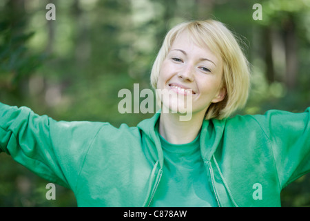 Deutschland, Bayern, Schäftlarn, Nahaufnahme von junge Frau im Wald mit Arme nach oben, Porträt, Lächeln Stockfoto