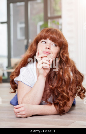 Deutschland, Berlin, Großaufnahme der jungen Frau auf Boden liegend, Lächeln Stockfoto