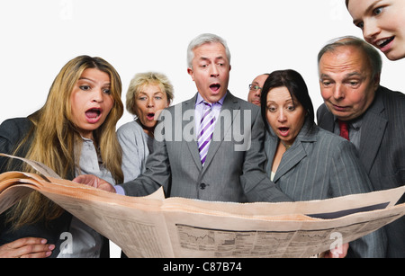 Business-Leute schockiert beim lesen Zeitung vor weißem Hintergrund Stockfoto