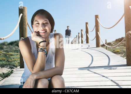 Spanien, Mallorca, junge Frau sitzt auf der Strandpromenade und der Mann im Hintergrund Stockfoto