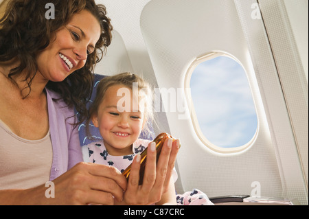 Deutschland, München, Bayern, Frau und Mädchen mit Handy in Economy-Class-Verkehrsflugzeug Stockfoto